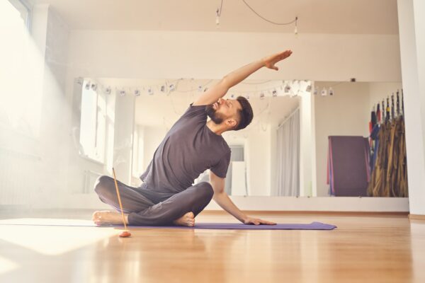 Handsome young man doing stretching exercise in yoga studio